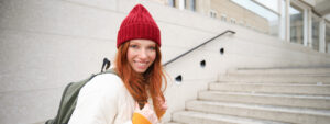 happy-young-girl-redhead-tourist-red-hat-with-backpack-walks-around-town-explores-city - Uni of Beds AI image for Website